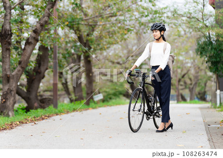 ビジネスカジュアル姿でロードバイクを押して歩く若い女性 ビジネスカジュアル姿でロードバイクを押して歩く若い女性 108263474