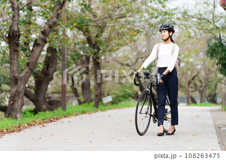 ビジネスカジュアル姿でロードバイクを押して歩く若い女性 108263475