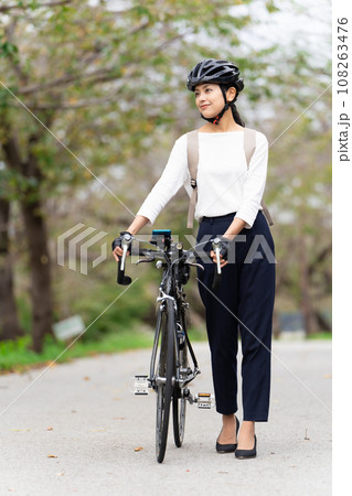 ビジネスカジュアル姿でロードバイクを押して歩く若い女性 108263476