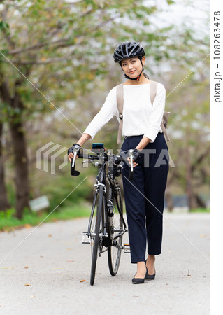ビジネスカジュアル姿でロードバイクを押して歩く若い女性 108263478