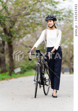 ビジネスカジュアル姿でロードバイクを押して歩く若い女性 108263482