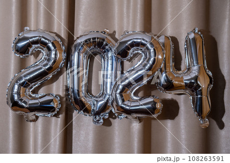 Happy new year 2024 metallic balloons on atlas textile background. Greeting card silver foil balloons numbers Christmas holiday concept. Celebration party congratulation Happy new year 2024 metallic balloons on atlas textile background. Greeting card silver foil balloons numbers Christmas holiday concept. Celebration party congratulation 108263591