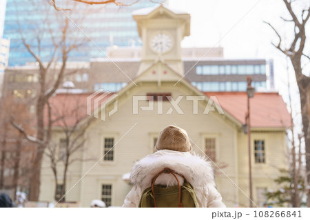 Woman tourist Visiting in Sapporo, Traveler in Sweater sightseeing Sapporo Clock tower with Snow in winter. landmark and popular for attractions in Hokkaido, Japan. Travel and Vacation concept 108266841