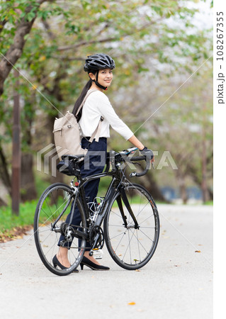 ビジネスカジュアル姿でロードバイクを押して歩く若い女性 後ろ姿 ビジネスカジュアル姿でロードバイクを押して歩く若い女性 後ろ姿 108267355