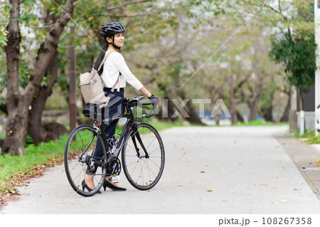 ビジネスカジュアル姿でロードバイクを押して歩く若い女性 後ろ姿 108267358