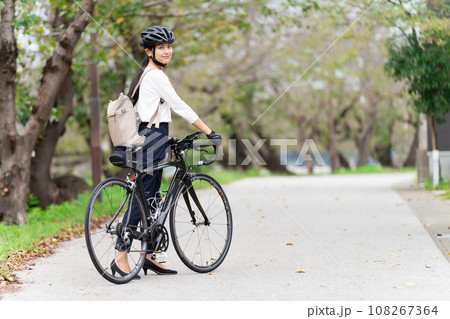 ビジネスカジュアル姿でロードバイクを押して歩く若い女性 後ろ姿 108267364
