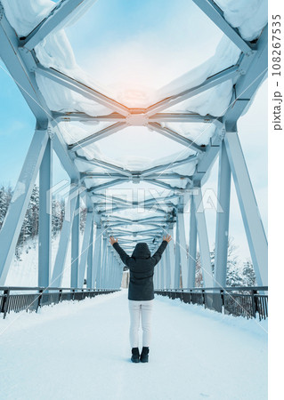 Woman tourist Visiting in Biei, Traveler in Sweater sightseeing Shirahige Waterfall bridge with Snow in winter. landmark and popular for attractions in Hokkaido, Japan. Travel and Vacation concept Woman tourist Visiting in Biei, Traveler in Sweater sightseeing Shirahige Waterfall bridge with Snow in winter. landmark and popular for attractions in Hokkaido, Japan. Travel and Vacation concept 108267535