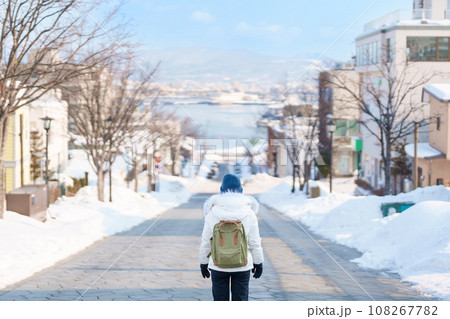 Woman tourist Visiting in Hakodate, Traveler in Sweater sightseeing Hachiman Zaka Slope with Snow in winter. landmark and popular for attractions in Hokkaido, Japan. Travel and Vacation concept 108267782
