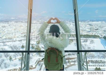 Woman tourist Visiting in Hakodate, Traveler in Sweater sightseeing view from Goryokaku Tower with Snow in winter. landmark and popular for attractions in Hokkaido, Japan.Travel and Vacation concept 108267818