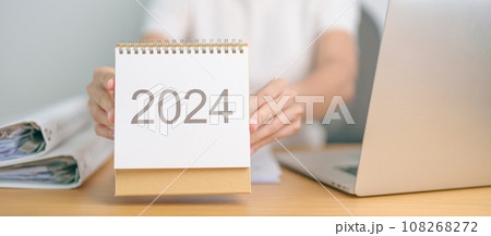 2024 Year Calendar on table with business woman using laptop computer. countdown, Happy New Year, Resolution, Goals, Plan,  Action, Mission and financial Concept 108268272