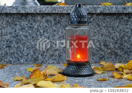All Souls' Day. A lit candle on the grave. Background with cemetery. Autumn time and holidays. Soulstice - remembrance of the dead - Halloween holiday. All Souls' Day. A lit candle on the grave. Background with cemetery. Autumn time and holidays. Soulstice - remembrance of the dead - Halloween holiday. 108268652