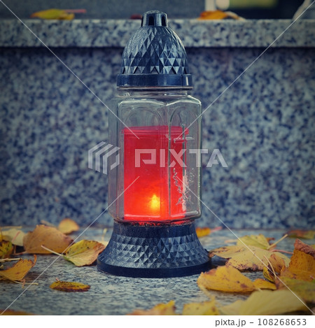 All Souls' Day. A lit candle on the grave. Background with cemetery. Autumn time and holidays. Soulstice - remembrance of the dead - Halloween holiday. 108268653