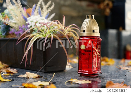 All Souls' Day. A lit candle on the grave. Background with cemetery. Autumn time and holidays. Soulstice - remembrance of the dead - Halloween holiday. 108268654