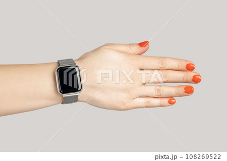 Closeup of woman hand with smartwatch with empty display handshaking with partner. Indoor studio shot isolated on gray background. 108269522
