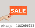 Closeup of woman hand showing card with sale inscription, special offer, shopping discounts. Indoor studio shot isolated on gray background. 108269533