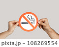 Closeup of woman hands showing card with no smoking sign, healthy lifestyle, healthy habits. Indoor studio shot isolated on gray background. 108269554