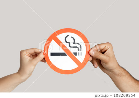 Closeup of woman hands showing card with no smoking sign, healthy lifestyle, healthy habits. Indoor studio shot isolated on gray background. Closeup of woman hands showing card with no smoking sign, healthy lifestyle, healthy habits. Indoor studio shot isolated on gray background. 108269554