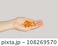 Closeup of woman hand handful of pills capsules, nutritional supplement, vitamins, medicine. Indoor studio shot isolated on gray background. 108269570