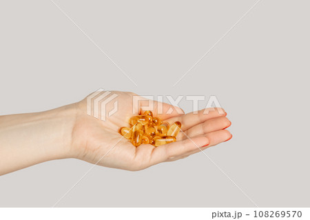 Closeup of woman hand handful of pills capsules, nutritional supplement, vitamins, medicine. Indoor studio shot isolated on gray background. Closeup of woman hand handful of pills capsules, nutritional supplement, vitamins, medicine. Indoor studio shot isolated on gray background. 108269570