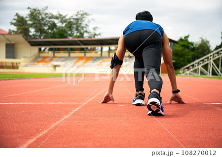 Asia male teenager getting ready starting to run on track in stadium 108270012