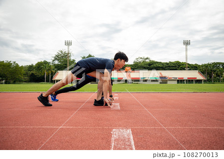Two Teenagers Take starting pose for Running in lane Stadium 108270013