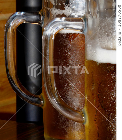 Glass handles of large half-liter wet mugs full of fresh light beer with misted sides Glass handles of large half-liter wet mugs full of fresh light beer with misted sides 108270500