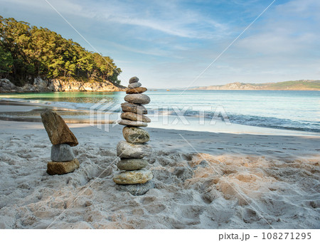 Pyramid stones balance on the sand of the beach. The object is in focus, the background is blurred Pyramid stones balance on the sand of the beach. The object is in focus, the background is blurred 108271295