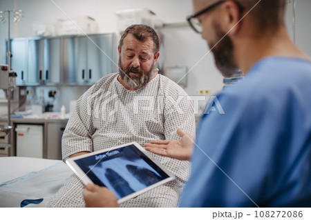 Doctor showing overweight patient chest x-ray, discussing test result in emergency room. Respiratory diseases in middle-aged men's health. Concept of health risks of overwight and obesity. 108272086