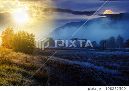 morning fog among trees on meadow in mountains with sun and moon at twilight in autumn. day and night time change concept. mysterious countryside scenery in morning light 108272500