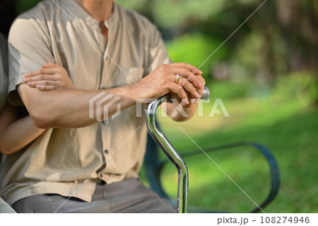 Adult daughter holding hand of middle age father on cane or walking stick showing love and support 108274946