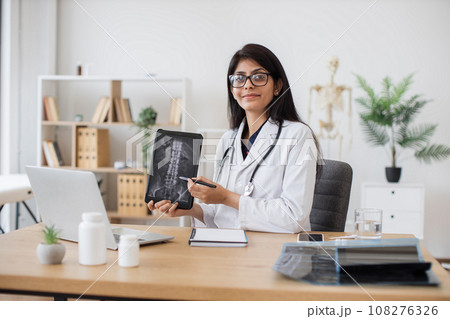 Female physician pointing at x-ray on tablet at workplace 108276326