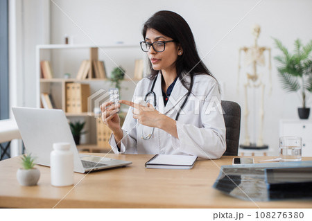 Doctor giving advice of pills during video call on laptop 108276380