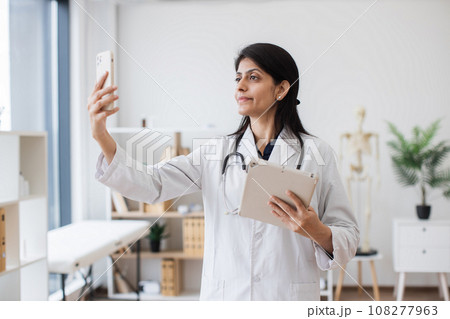 Hindu doctor using tablet and mobile for online consultation 108277963