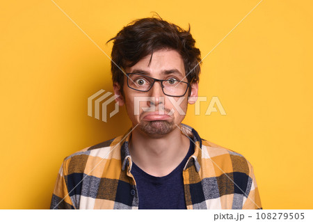 Offended young guy looking at camera isolated on yellow studio wall 108279505