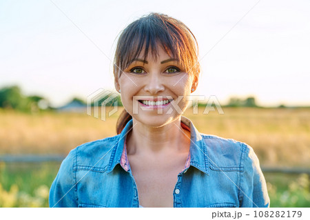 Portrait of smiling middle aged woman looking at camera, summer countryside 108282179