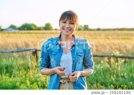 Portrait of smiling middle aged woman looking at camera, summer countryside 108282180