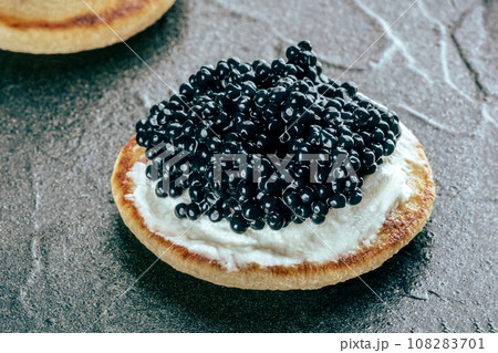 A blini with caviar and cream cheese, a closeup on black 108283701