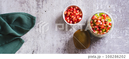 Tropical fruit kiwi, fresh yogurt and pomegranate seeds in a glass top view web banner Tropical fruit kiwi, fresh yogurt and pomegranate seeds in a glass top view web banner 108286202