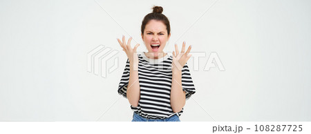 Image of angry woman shouts and shakes hands, stands in casual clothes over white background Image of angry woman shouts and shakes hands, stands in casual clothes over white background 108287725