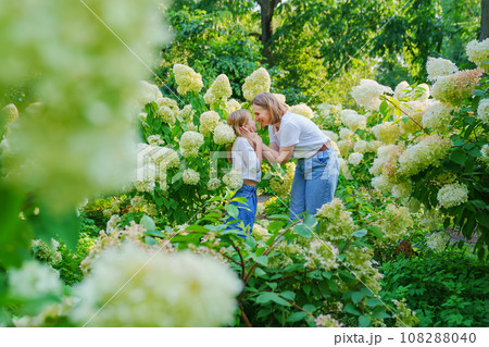 mother and daughter in flowering hydrangea bushes. mother and daughter in flowering hydrangea bushes. 108288040