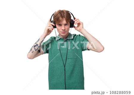 young positive slender student european man with red hair listens to music in headphones with a wire young positive slender student european man with red hair listens to music in headphones with a wire 108288059