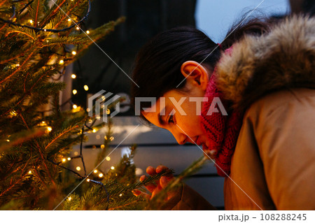 side view of girl watching christmas tree lights in the evening 108288245