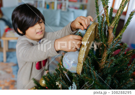 high angle view on hands of child putting decoration on christmas tree high angle view on hands of child putting decoration on christmas tree 108288295