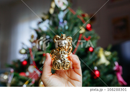 close up view on golden christmas teddy bear toy in front of christmas tree close up view on golden christmas teddy bear toy in front of christmas tree 108288301