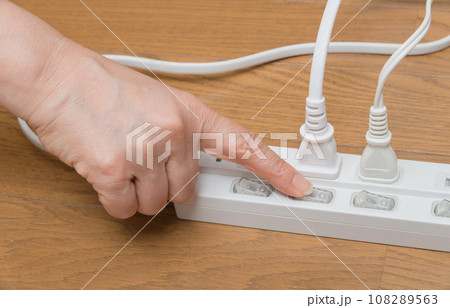 【タップにコンセントのスイッチを押す主婦】 【タップにコンセントのスイッチを押す主婦】 108289563
