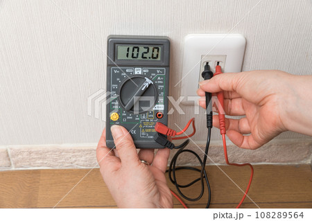 【テスターでコンセントの電圧を計る主婦】 108289564