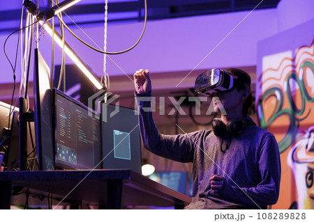 Hacker doing illegal activity in vr headset and exploring metaverse while breaking law. Criminal hacking server in virtual reality simulation while making gestures with hands Hacker doing illegal activity in vr headset and exploring metaverse while breaking law. Criminal hacking server in virtual reality simulation while making gestures with hands 108289828