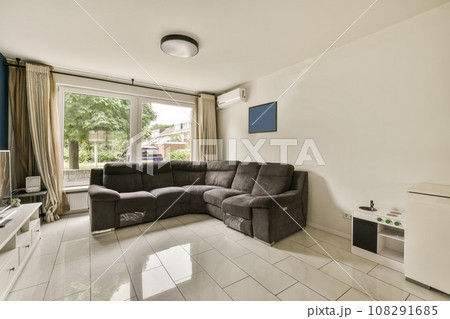 a living room with a couch, tv and large window looking out onto the street in front of the house a living room with a couch, tv and large window looking out onto the street in front of the house 108291685