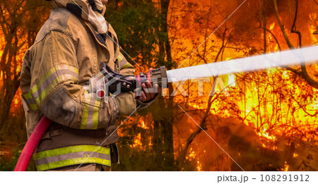 Firefighter spray water to bushfire. Tropical wildfires release carbon dioxide (CO2) emissions that contribute to climate change and global warming. Firefighter spray water to bushfire. Tropical wildfires release carbon dioxide (CO2) emissions that contribute to climate change and global warming. 108291912