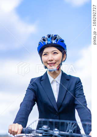 ヘルメットを被り自転車で通勤する若い女性 108292727